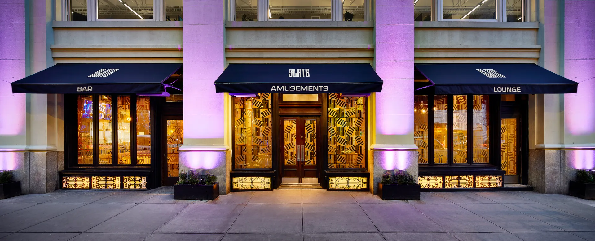 Slate NYC entrance with illuminated Bar, Amusements, and Lounge awnings