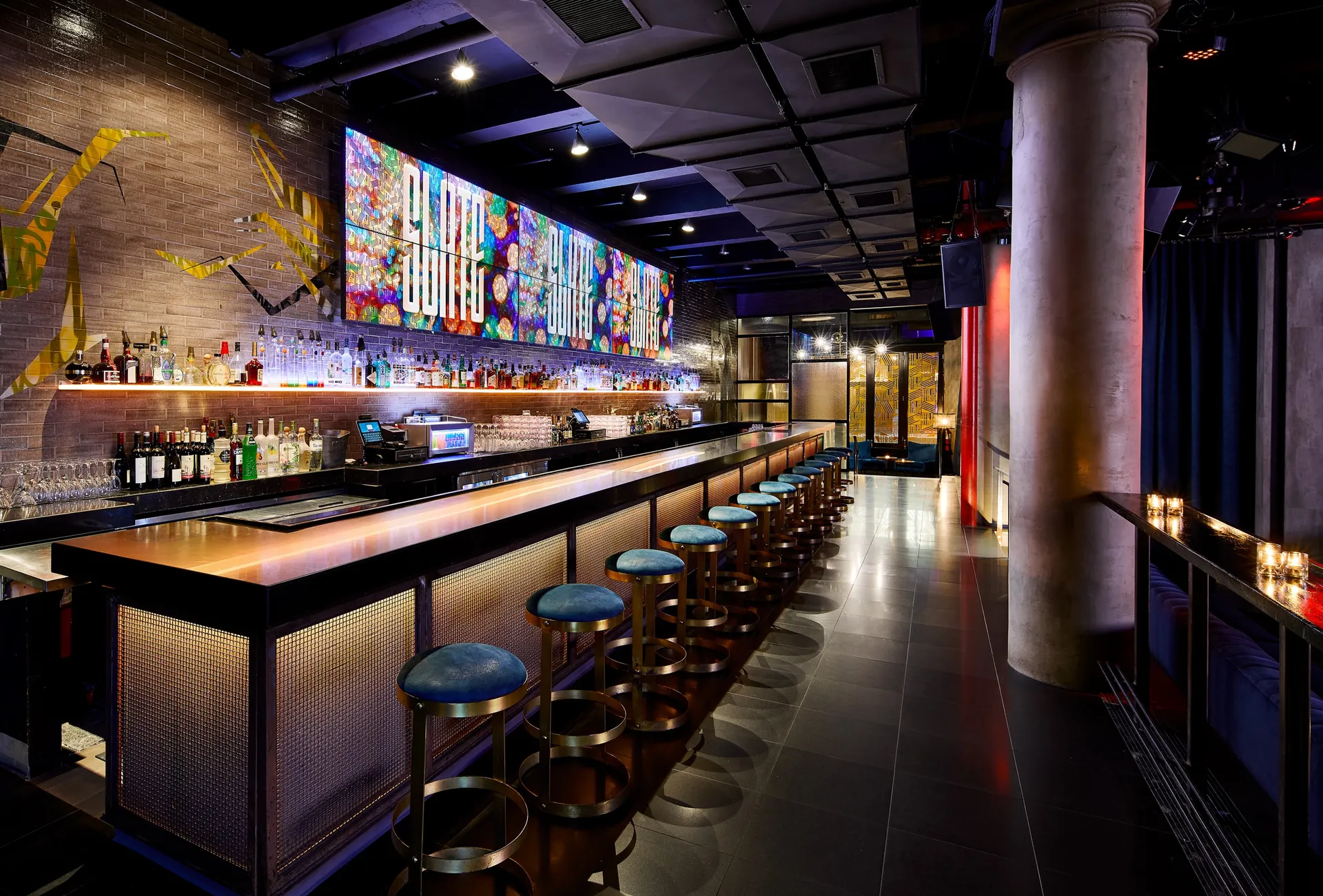 Slate NYC bar with blue stools and a long illuminated counter