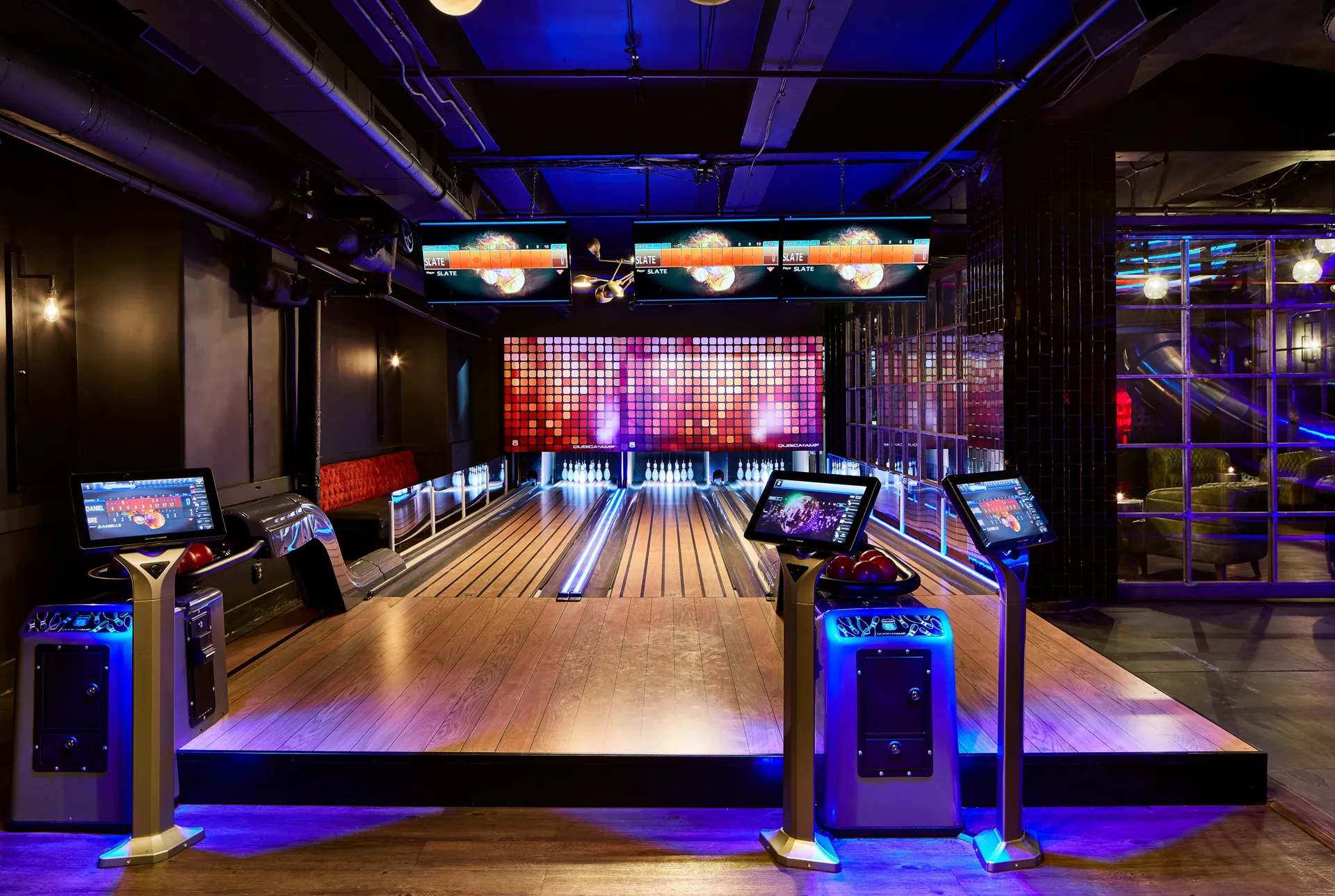 Slate NYC bowling lanes with colorful screens and blue lighting